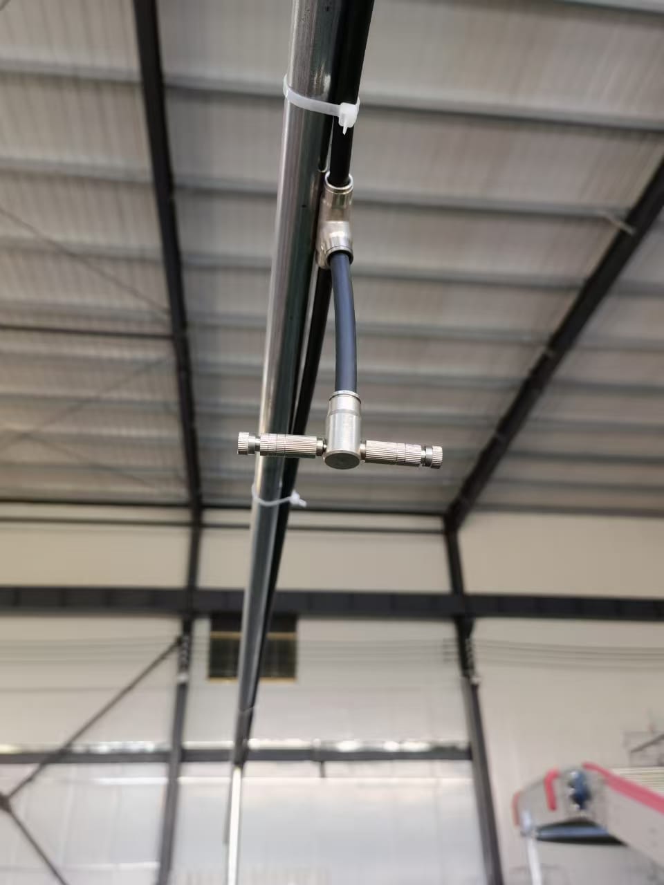 Automated high-pressure misting system with stainless steel nozzles installed in commercial multi-tier poultry house